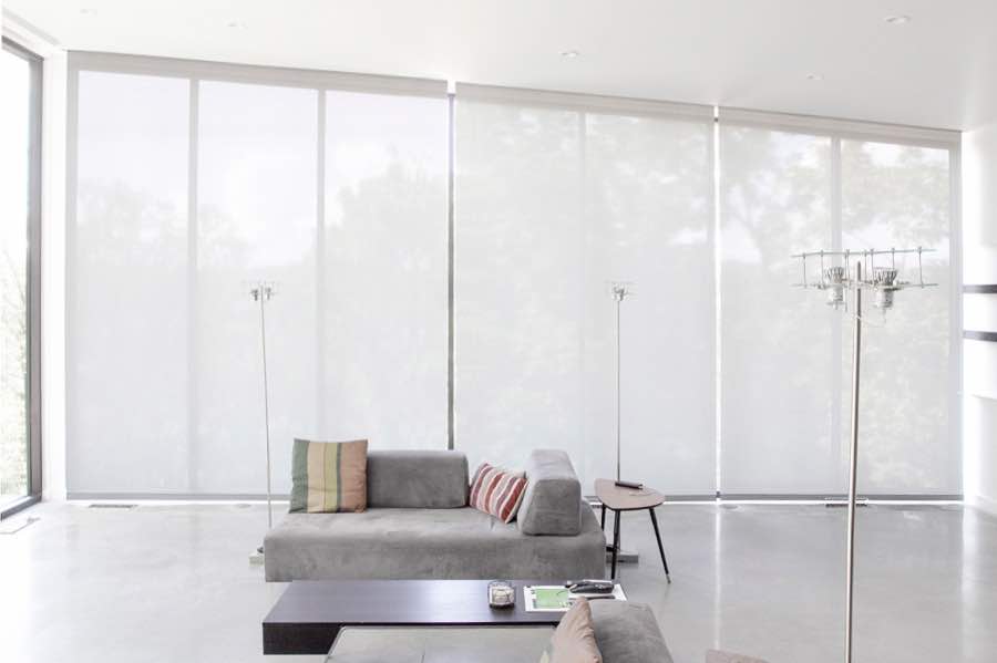 Motorized window shades make controlling natural light effortless in your Fort Lauderdale great room. White motorized shades on a wall of tall great room windows
