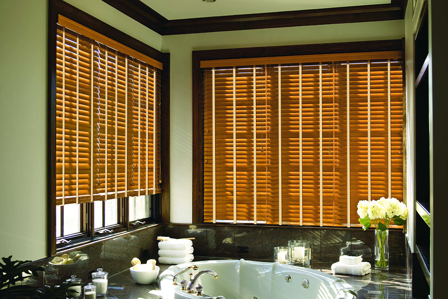Brown wood shutters on large windows in a green bathroom