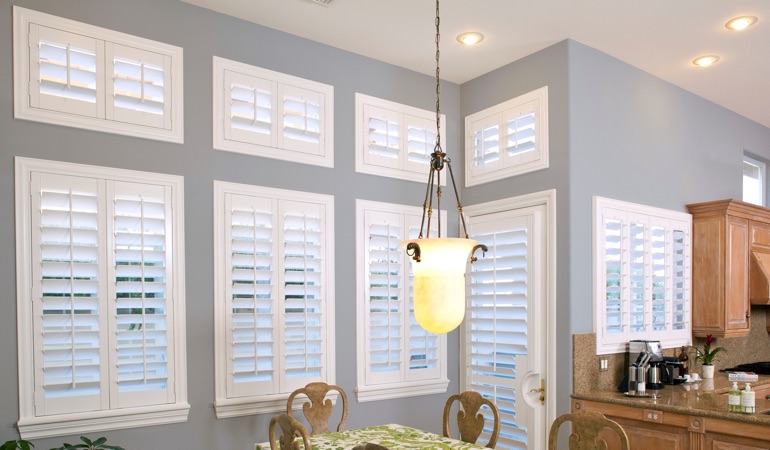 Interior Shutters can solve both sun glare and heat loss problems. White plantation shutters in kitchen