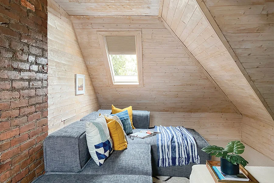 A tan window shade on a skylight in an attic sitting nook