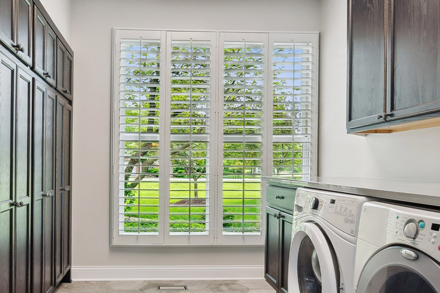 Find the perfect level of natural light for your Fort Lauderdale laundry room with interior shutters. White Polywood shutters letting light through a laundry room window